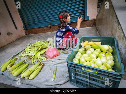 Kathmandu, Bagmati, Nepal. 21. August 2022. Ein kleines Mädchen, das mit einem Handy spielt, verkauft am 21. August 2022 trockene Hühneraugen vor einem Haus in Kathmandu, Nepal. (Bild: © Sunil Sharma/ZUMA Press Wire) Stockfoto