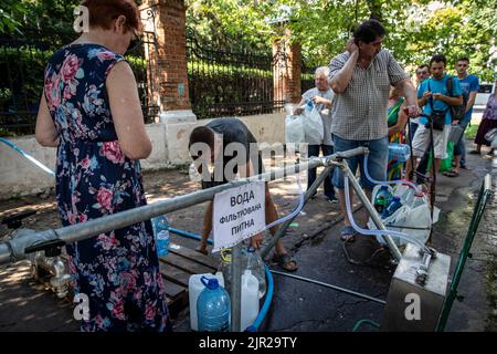 Mykolaiv, Ukraine. 19. August 2022. Die Bewohner warten an einer Wasserversorgungsstation auf Wasser, da der Beschuss die Hauptwasserversorgung in der Stadt Mykolaiv in der Ukraine unterbrochen hat. Mykolaiv, die strategische Stadt der Ukraine auf der Südseite mit Zugang zum Schwarzen Meer und ist eines der wichtigsten Schiffbauzentren, hatte früher eine Bevölkerung von 476.101 (2021 estens.), wurde aber nach der umfassenden Invasion von Russland stark belagert und bombardiert. Als ukrainische Beamte haben Befangenheit behauptet, um ihr Territorium zurückzugewinnen, und eine Gegenoffensive im Süden, einschließlich Mykol, durchgeführt Stockfoto