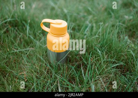 Nahaufnahme von Edelstahl-Thermoskannen auf grünem Gras mit Kopierraum. Stockfoto