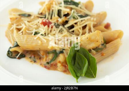 Nahaufnahme Makro von gekochten glutenfreien Pasta Dinner Rezept mit Käse und Tomaten und frischen Basilikum Garnierung Stockfoto