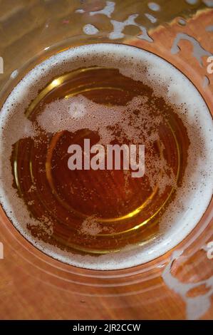 Ein Glas Bier von oben gesehen, in dem man die Flüssigkeit im Inneren in einer Makroaufnahme sieht. Stockfoto
