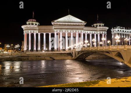 Beleuchtetes archäologisches Museum und Augenbrücke bei Nacht in Skopje, der Hauptstadt von Nord-Mazedonien. Stockfoto