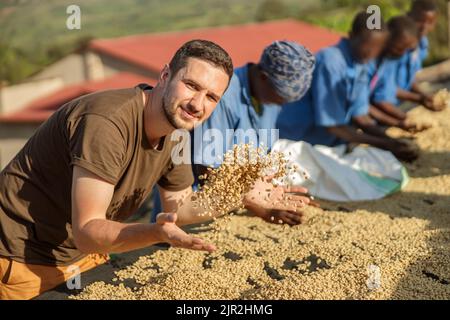 Junger Mann wirft Kaffeebohnen mit den Händen Stockfoto