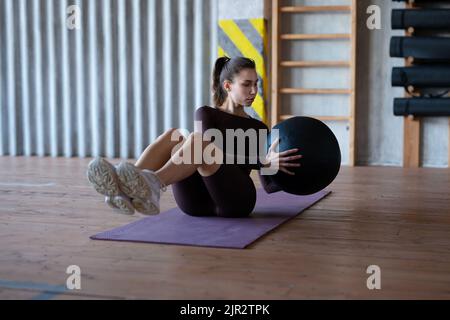 Fit junge Frau beim Training mit Medizinball, weibliche Sportlerin beim abs-Core-Workout im Fitnessstudio. Stockfoto