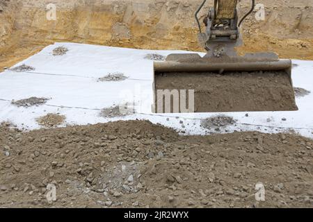 Den Schotter auf das Filtervlies legen Stockfoto