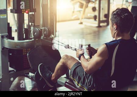 Junger, fitter Mann, der im Fitnessstudio am Simulator arbeitet Stockfoto