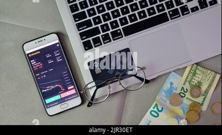 Laptop und Telefon, um Bitcoin auf der Binance Krypto-Börse während des Marktabsturzes zu kaufen. Trading, Spot, Staking. Freelance-Flatlay für den Arbeitsbereich Stockfoto