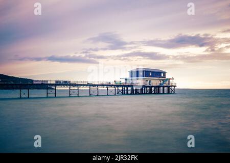 AUGUST 2022, ISLE OF WIGHT, GROSSBRITANNIEN. Ein Langzeitfoto des Piers in Totland Bay bei einem Abenduntergang mit einem atemberaubenden Himmel entlang der Küste. Stockfoto