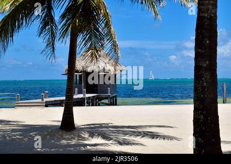Ein kleiner Palapa in einem Strandresort, über blauem Wasser, an einem sonnigen Tag auf Ambergris Caye, San Pedro, Belize. Stockfoto