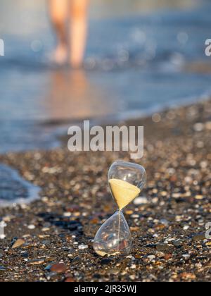 Person, die in der Nähe von Hourglass am Strand an der Küste läuft Stockfoto