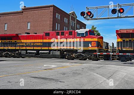 EMPORIA, KANSAS – 13. AUGUST 2022 Kansas City Southern Lokomotiven, die einen langen Zug von Autotransportwagen ziehen, werden am Hauptzugübergang in der Innenstadt von Emporia angehalten und dann auf einem Abstellgleis aufgesetzt, um 3 BSNF-Expresszüge auf den Hauptgleisen Ost und Ost ausfahren zu lassen. Stockfoto