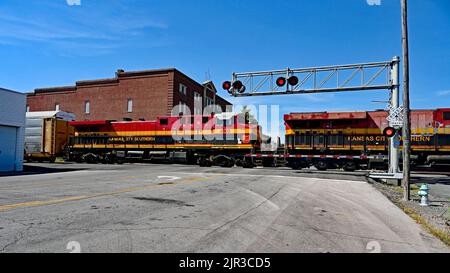 EMPORIA, KANSAS – 13. AUGUST 2022 Kansas City Southern Lokomotiven, die einen langen Zug von Autotransportwagen ziehen, werden am Hauptzugübergang in der Innenstadt von Emporia angehalten und dann auf einem Abstellgleis aufgesetzt, um 3 BSNF-Expresszüge auf den Hauptgleisen Ost und Ost ausfahren zu lassen. Stockfoto