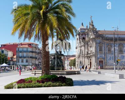 Palme mit Fonte dos Leões (Löwenbrunnen) und barocke Igreja Carmo (Carmo-Kirche) mit blau-weißen Fliesen dahinter, Porto, Portugal. Stockfoto