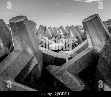 Ein monochromes Bild von Betonwällen mit einem Glatzenkopf in der Mitte mit dem Rücken zur Kamera. Stockfoto