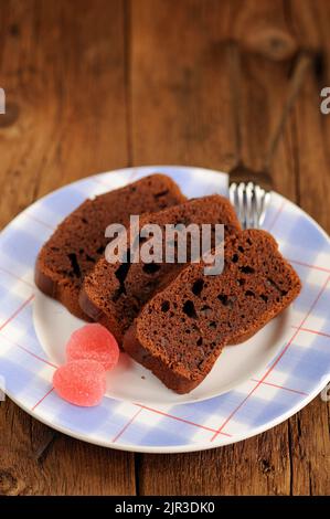 Stücke von hausgemachten Schokoladenkuchen mit rosa Süßigkeiten auf Holzhintergrund mit Copyspace vertikal Stockfoto