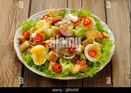 Salat Caesar mit Pilzen, Eiern, Chili und Rettich auf Holzhintergrund horizontal Stockfoto