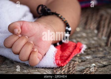 Gefaltete Kleine Finger Von Hungrig Einen Monat Oder Vier Wochen Alt Neugeborenes Mädchen Mit Traditionellen Schwarzen Perlen Armreifen Vor Pech Achtung Zu Schützen Stockfoto