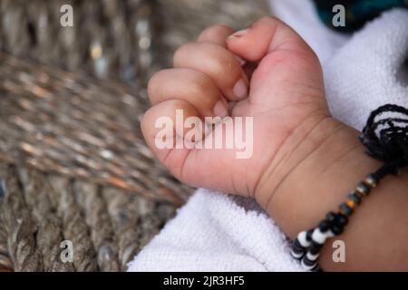 Gefaltete Kleine Finger Von Hungrig Einen Monat Oder Vier Wochen Alt Neugeborenes Mädchen Mit Traditionellen Schwarzen Perlen Armreifen Vor Pech Achtung Zu Schützen Stockfoto