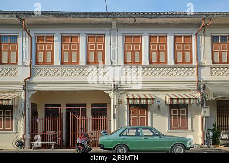 Eine Reihe von sino-portugiesischen oder Peranakan-Häusern in der Dibuk Road in der Altstadt von Phuket Town, Phuket, Thailand, ein altes Auto, das davor geparkt ist Stockfoto