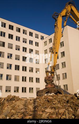 Haufen von Schutt und Arbeitskran vor einem modernen architektonischen Gebäude. Stockfoto