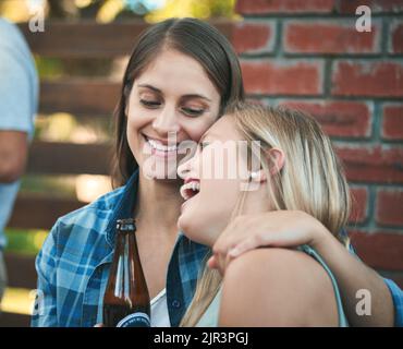 Zwei glückliche junge Frauen, die bei einem Get Together mit ihren Freunden ein paar Biere genießen. Stockfoto