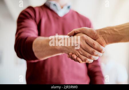 Vergnügen, Geschäfte mit Ihnen zu machen. Nahaufnahme von zwei Händen, die nicht zu erkennen sind, um bei der Arbeit in einem Büro die Hände zu grüßen und zu schütteln. Stockfoto