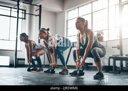 Machen Sie weiter mit Ihren Fitnesszielen. Drei junge Frauen trainieren gemeinsam. Stockfoto