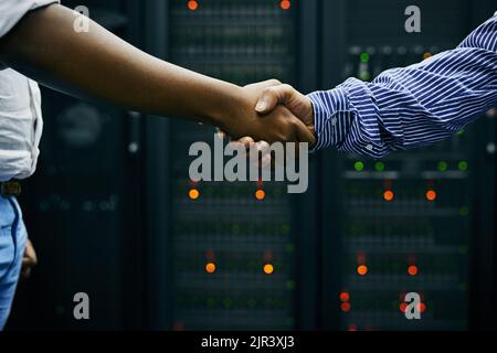 Zwei Männer, die sich in einem Rechenzentrum die Hände schütteln. Stockfoto