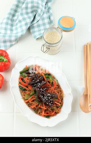 Bulgogi Japchae, Gebratene koreanische Vermicelli Nudeln mit Gemüse und Rindfleisch, gekrönt mit weißem Sesamsamen. Traditionelle Koreanische Küche Stockfoto