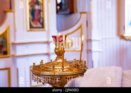 Brennende Kerzen im Tempel, Wachskerzen vor dem Hintergrund eines Kreuzes mit einem Kruzifix, dem Begriff der christlichen Religion, angezündet Stockfoto