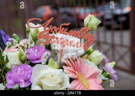 Weiße Geschenkkarte mit der Aufschrift glücklicher Tag des Lehrers in einem Strauß von hellen schönen bunten Rosen, das Konzept der Glückwünsche auf die h Stockfoto