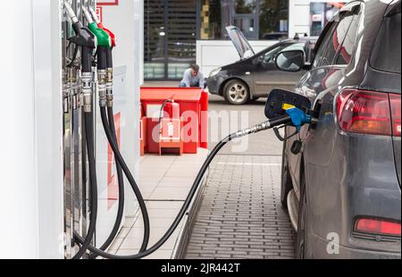 Tankstelle. Zum Auftanken die Kraftstoffdüse anfassen. Das schwarze Auto wird von befeuert. Erwachsener attraktive kaukasischen Mann Dienstleistungen sein Auto, selecteve Fokus. Stockfoto