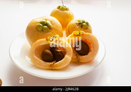 Ganze und halbiert Rosenäpfel mit Samen in Einem weißen Teller Stockfoto