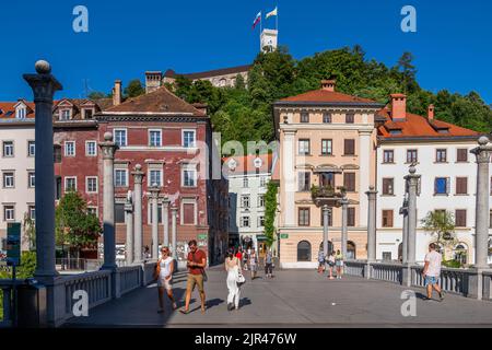 Ljubljana, Slowenien - 13. Juli 2022: Blick auf die Altstadt und den Burgberg von der Cobblers-Brücke (Schuhmacher), Wahrzeichen der Stadt. Stockfoto