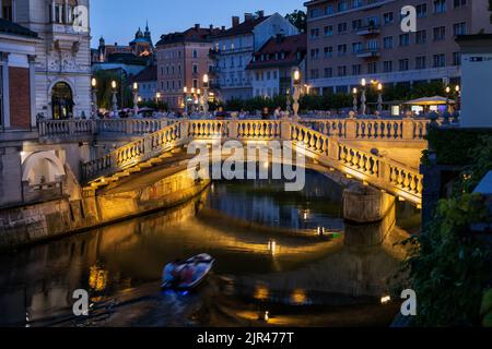 Ljubljana, Slowenien - 13. Juli 2022: Dreifachbrücke (Slowenisch: Tromostovje) über den Fluss Ljubljanica bei Nacht, Wahrzeichen der Stadt. Stockfoto