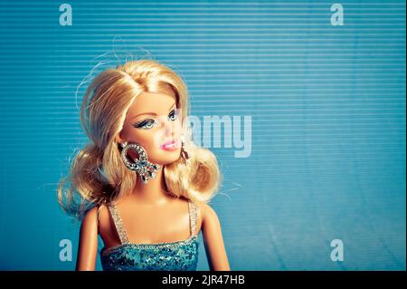 Blonde Barbie-Puppe in blauem Kleid auf blauem Hintergrund Stockfoto