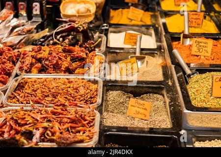 Sortiment verschiedener Gewürzsorten auf dem Boqueria Markt in Barcelona (Spanien), selektiver Fokus auf den getrockneten Paprika auf der linken Seite des Stockfoto