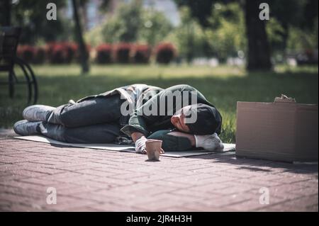 Dunkelhäutiger Mann, der im Park auf dem Boden schläft Stockfoto