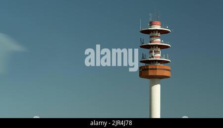Rot-weißer Kommunikationsturm gegen den Himmel Stockfoto