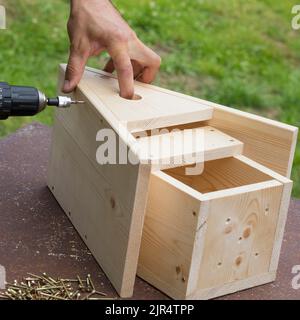 Nestkastenserie, Schritt 7/13: Giebelplatte zwischen den beiden Dachplatten verschrauben Stockfoto