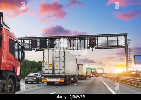 Dichter Verkehr von Lastkraftwagen auf einer Hochgeschwindigkeitsstraße mit einer Geschwindigkeit von 110 Kilometern pro Stunde. Abendansicht der Autobahn Stockfoto