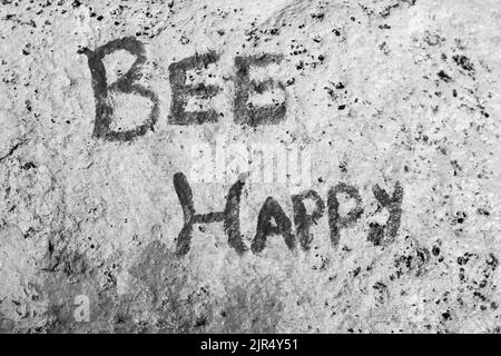 Bee Happy auf einen Felsen gemalt als schöne Gartendekoration in schwarz-weiß einfarbig. Stockfoto