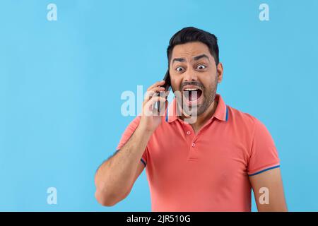 Porträt eines überraschten jungen Mannes, der auf dem Smartphone spricht Stockfoto