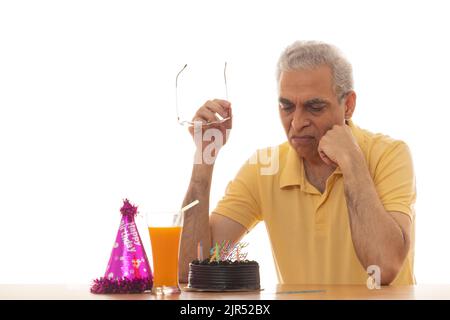 Trauriger älterer Mann, der seinen Geburtstag einsam feiert Stockfoto