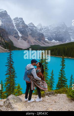 Moränensee während eines kalten verschneiten Tages in Kanada, türkisfarbenes Wasser des Moränensees mit Schnee. Banff National Park of Canada Canadian Rockies. Junge Paare, Männer und Frauen, die am See stehen Stockfoto