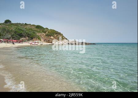 Typisch sardischen Strand (Cala Sinzias) mit kristallklarem Meer und die Vegetation in den Bergen mit Blick auf das Meer. Stockfoto