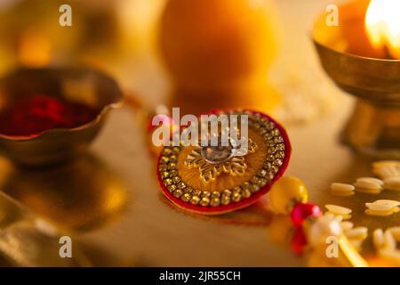 Nahaufnahme eines schönen Rakhi, der auf einem Teller mit Diya und Reis gehalten wird Stockfoto