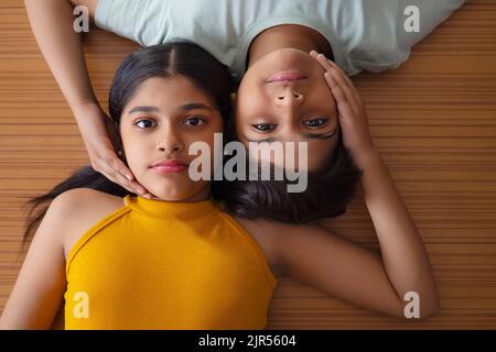 Nahaufnahme von Jungen und Mädchen, die auf Holzboden liegen Stockfoto