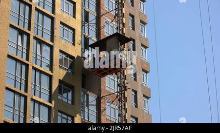 Kiew, Ukraine - 24.04.2019: Arbeiter ziehen auf den Aufzug des Bauwerks. Blauer Himmel Hintergrund. Stockfoto