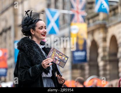 Royal Mile, Edinburgh, Schottland, Großbritannien, 22.. August 2022. Fransen-Darsteller: Eine attraktive Frau in historischen Kostümen verteilt Flyer für eine Show über die Wichtigkeit, ernst zu sein. Kredit: Sally Anderson/Alamy Live Nachrichten Stockfoto